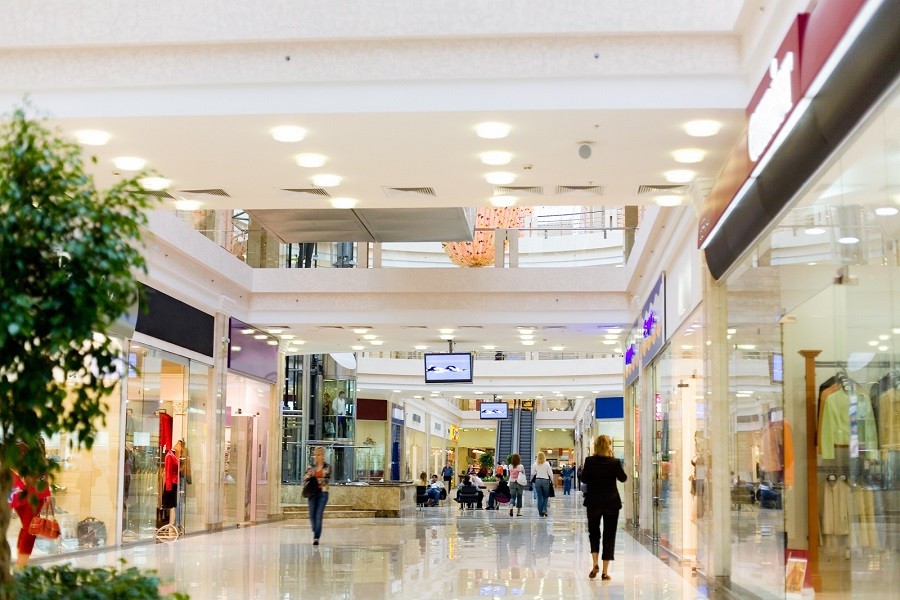 Retail mall environment with people walking by stores under the watchful eye of security systems. 