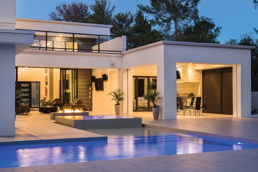 Exterior of a luxury backyard with sophisticated illumination and an inground pool. 