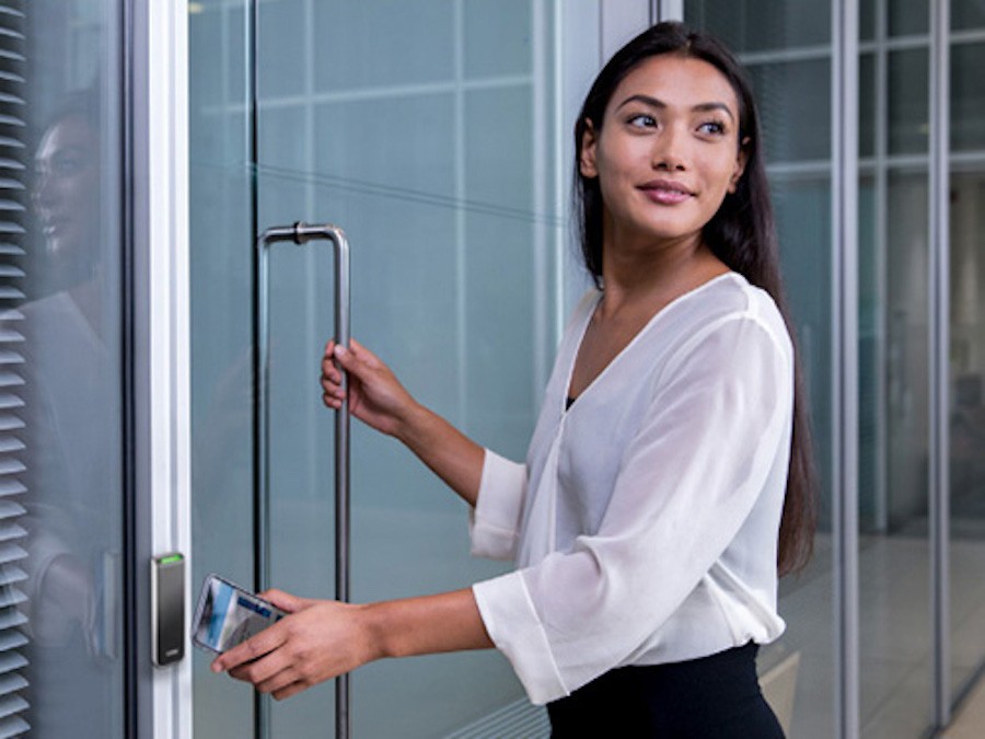 A woman uses her mobile phone to enter a business facility. 