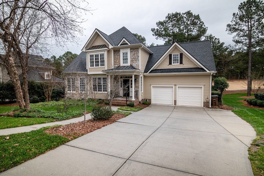 A beautiful home shown from the driveway, leafless trees surrounding it. 