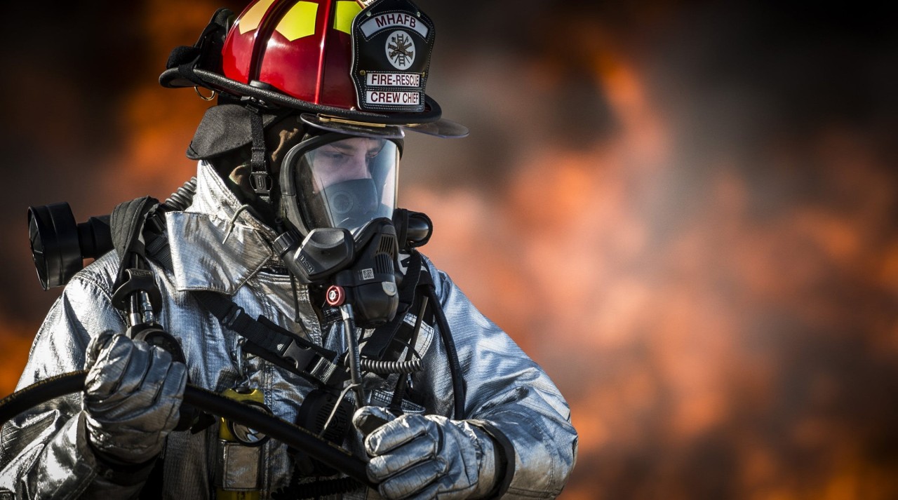 Close up shot of a fireman, fire in the background.