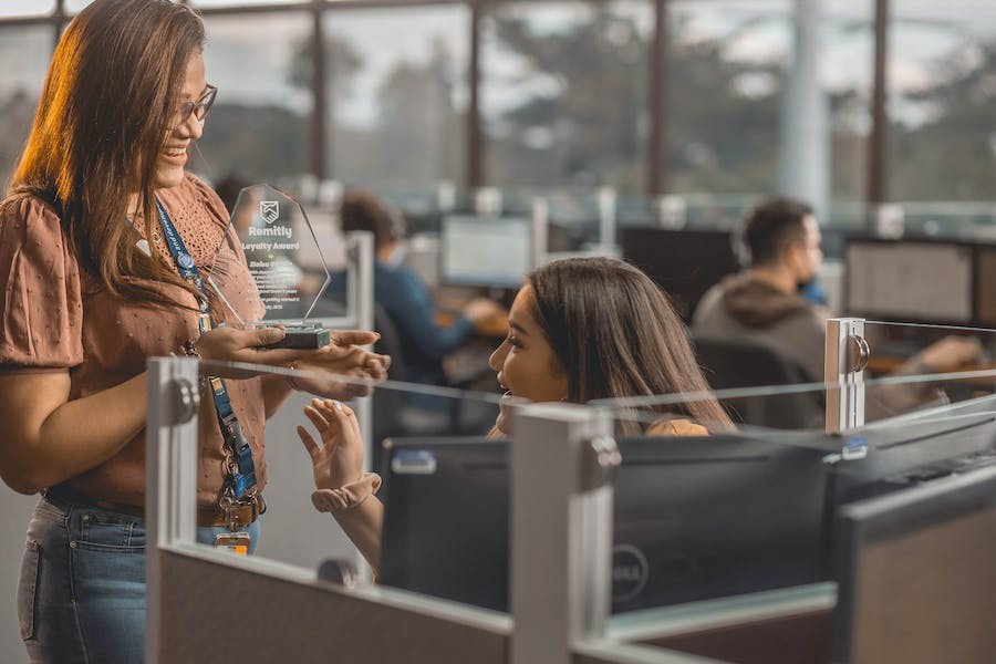 Employees talking over their cubicles in an office space.